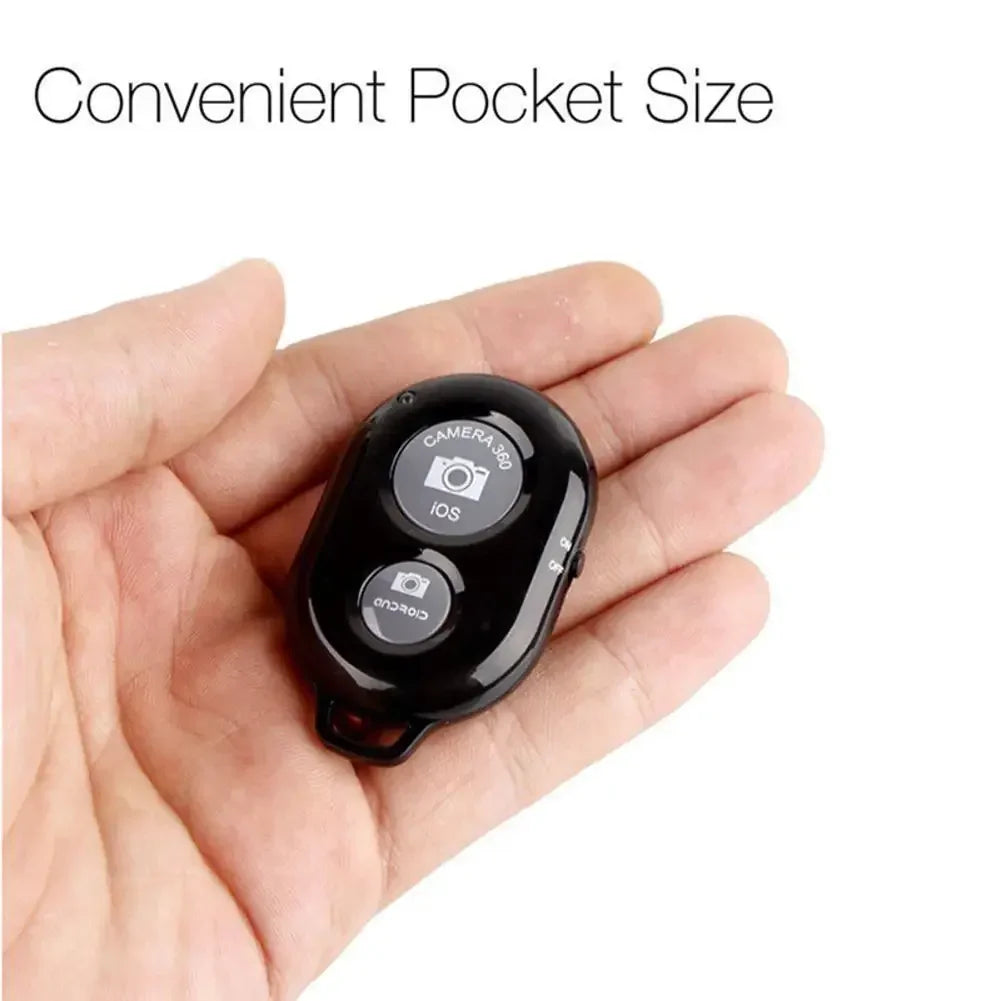 Black plastic Bluetooth camera shutter remote for iOS and Android, held in a person's palm.