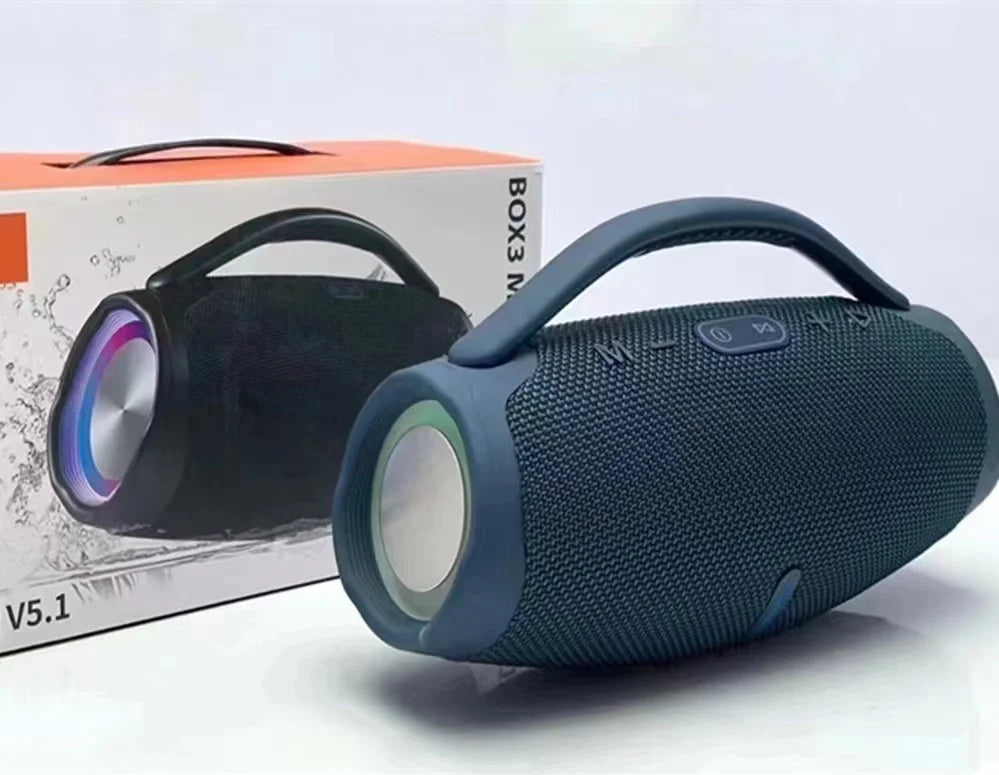 Navy blue portable Bluetooth speaker with integrated carry handle and side RGB lighting, shown next to its product box.