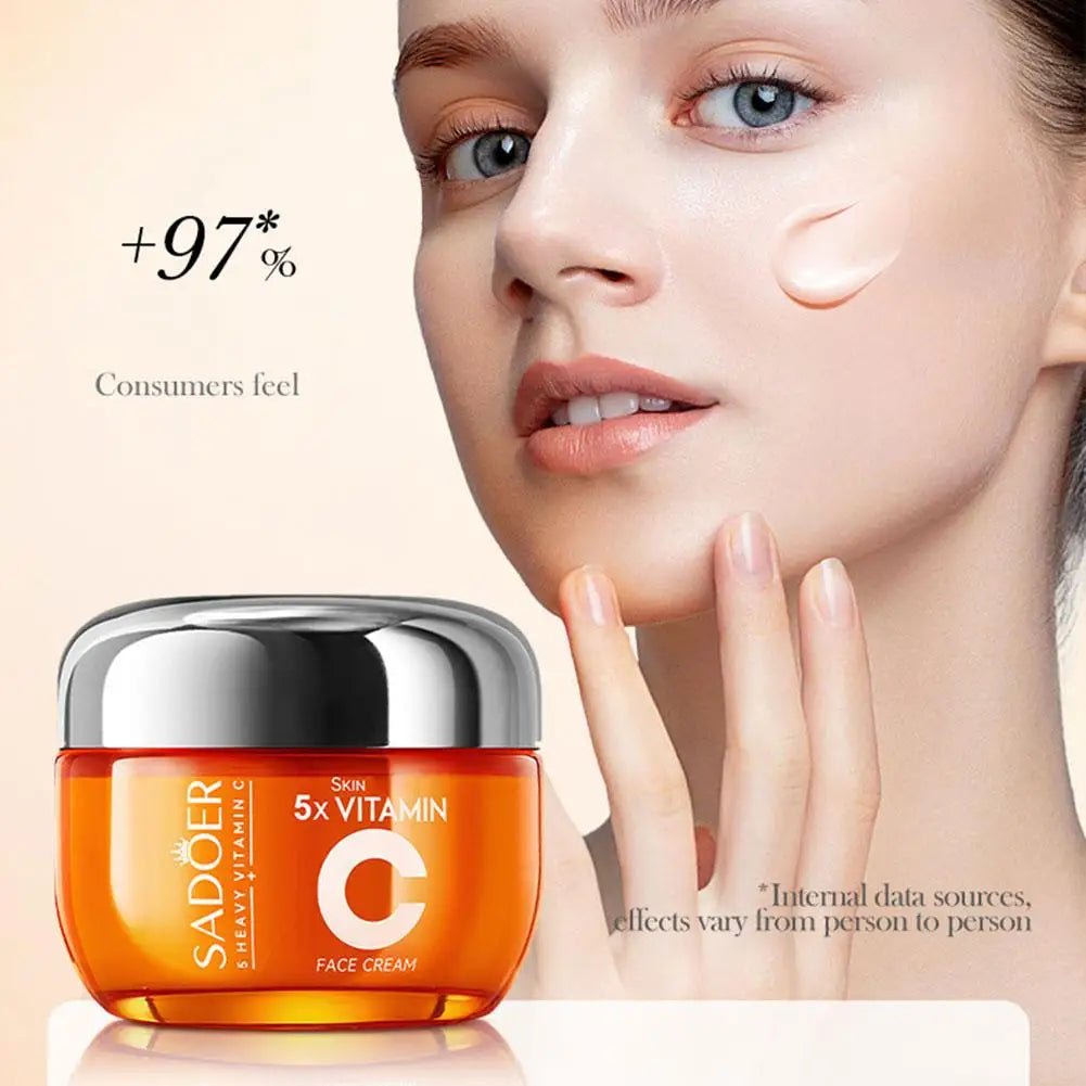 Orange jar of Vitamin C face cream with a silver lid next to a woman with smooth skin and cream on her cheek.