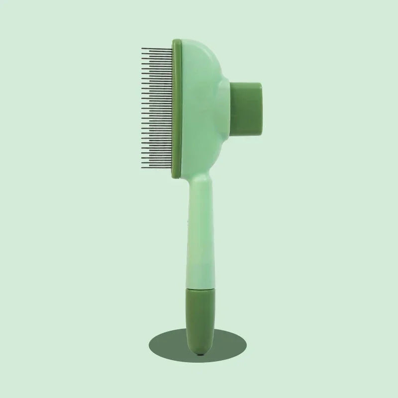 Sage green pet grooming brush with fine metal bristles and a sturdy handle, set against a matching pastel background.