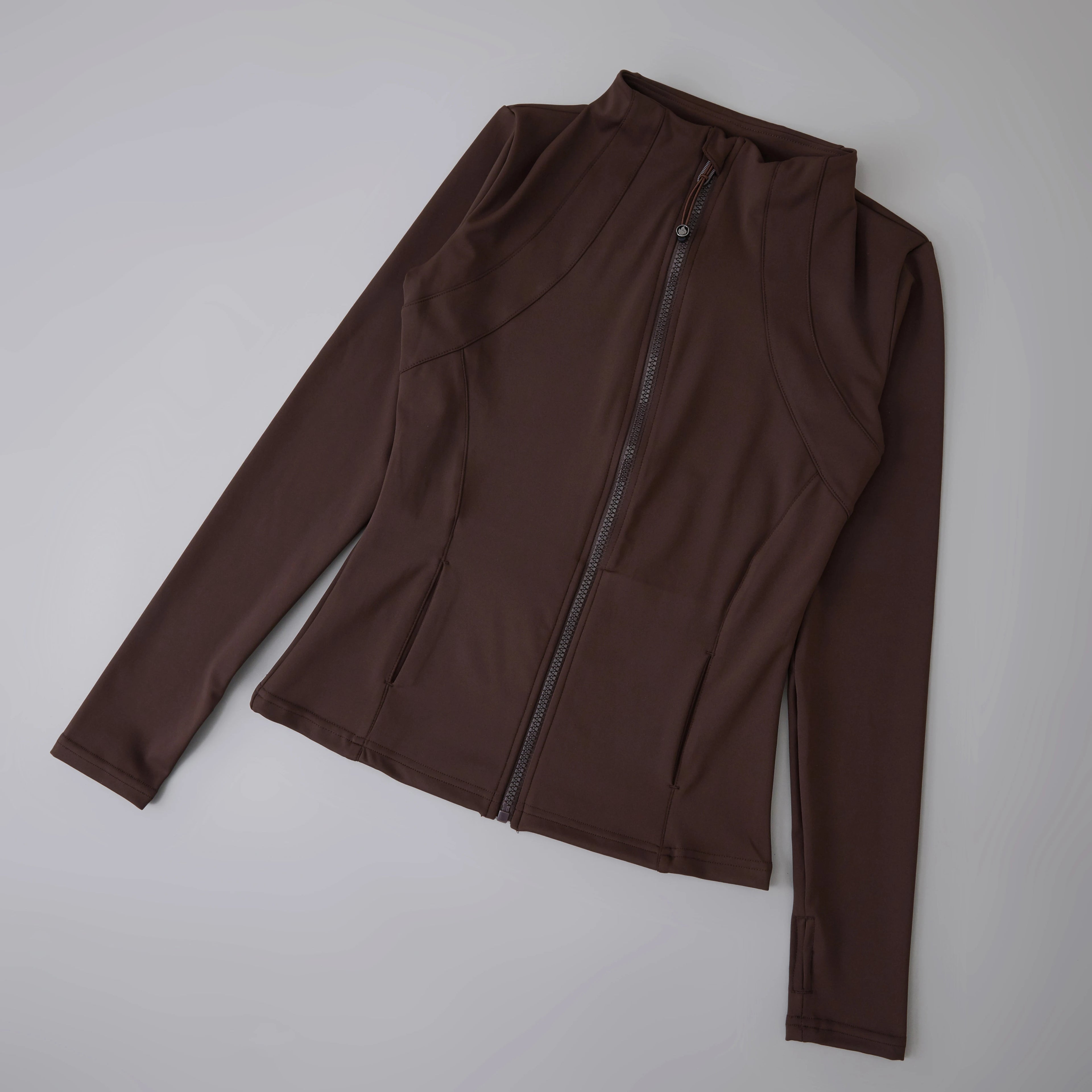 Dark brown, fitted athletic zip-up jacket with a high neck, long sleeves with thumbholes, and two front pockets.