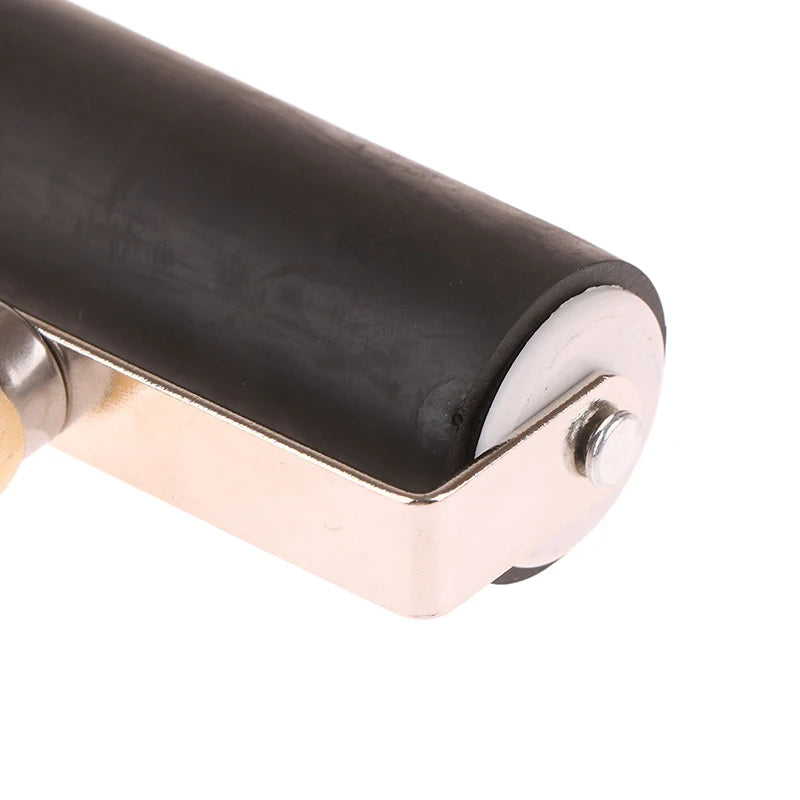 Craft roller with a black rubber cylinder, silver metal frame, and wooden handle for printmaking and craft projects.