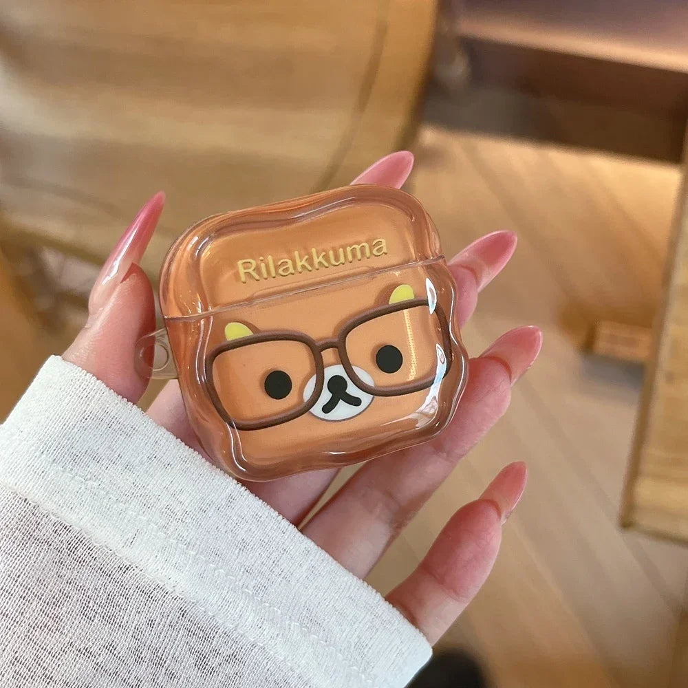 Clear silicone AirPods case featuring a brown Rilakkuma bear design with glasses, held in a hand.