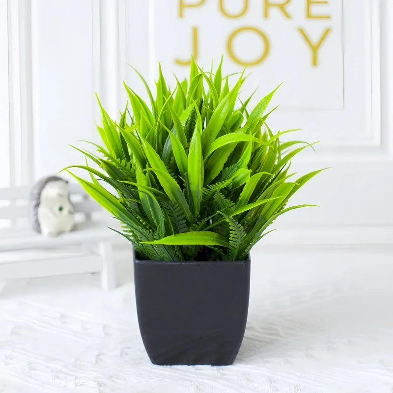 Vibrant artificial green grass plant in a sleek, square black pot, sitting on a white surface.