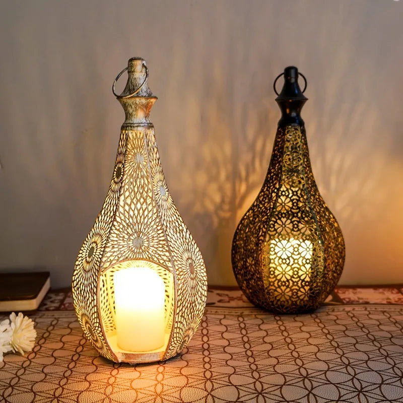 Two Moroccan iron lanterns with cutout patterns; one distressed white, one dark, each holding a glowing candle.