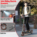 Dark gray foldable electric scooter with 8.5-inch black tires featuring red rims, ridden outdoors by a man.