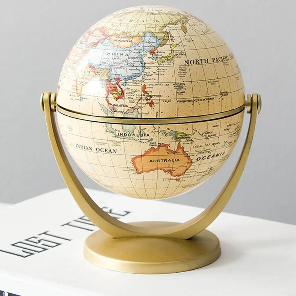 Vintage-style desk globe in cream with colourful map details, supported by a brushed gold metal swivel stand.