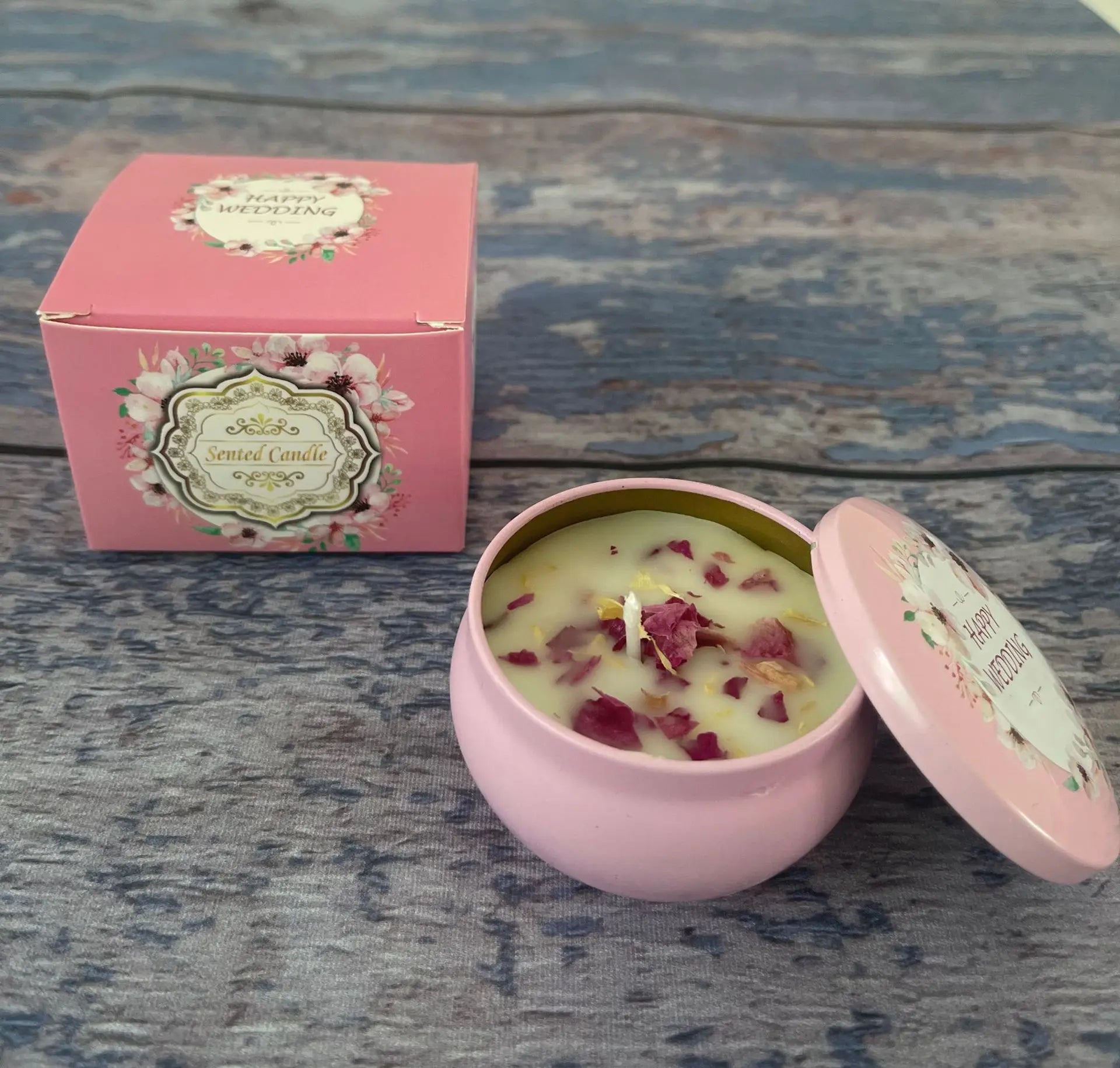 Pink "Happy Wedding" scented candle in a decorative tin with matching gift box, topped with dried flower petals.