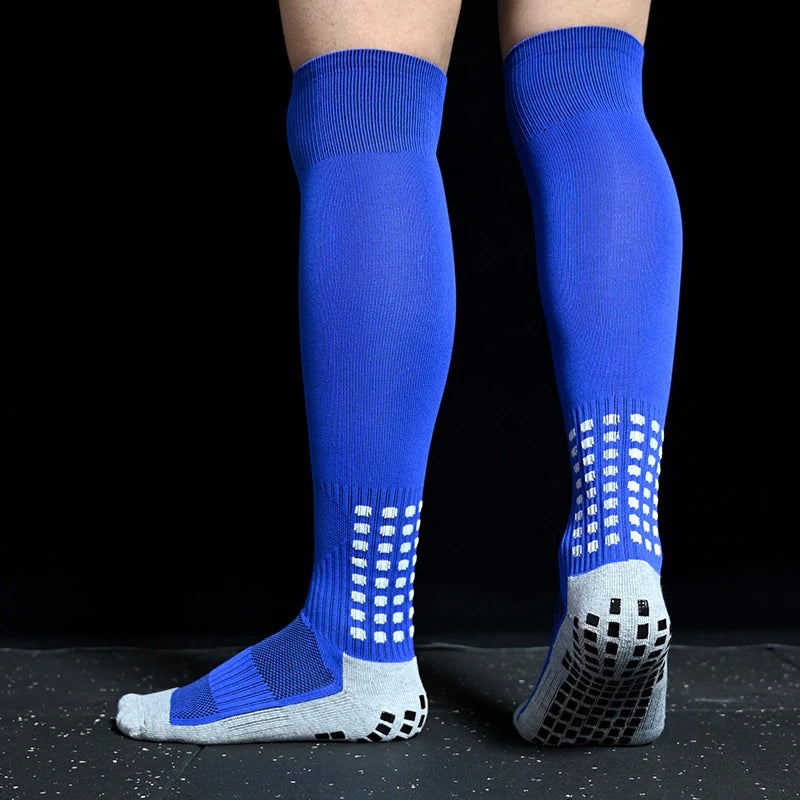 Blue knee-high sports socks with white grid detailing and black non-slip grip soles on a black background.