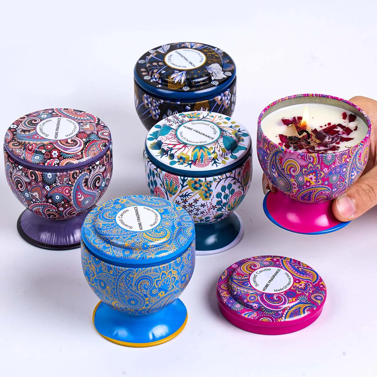 Set of five vibrant, pedestal-style tins with patterned lids and matching colourful, scented natural wax candles.