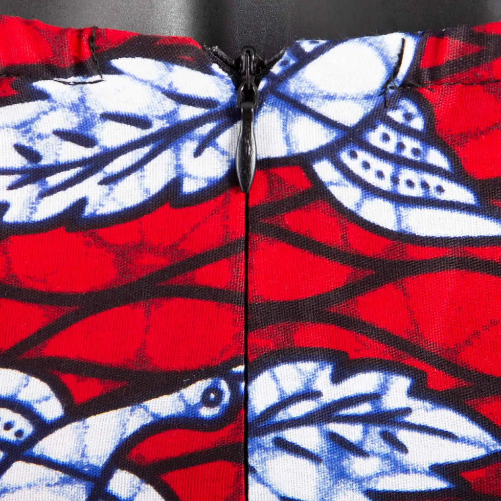 Close-up of a garment with a black zip, featuring a vibrant red, blue, and white floral leaf print pattern.