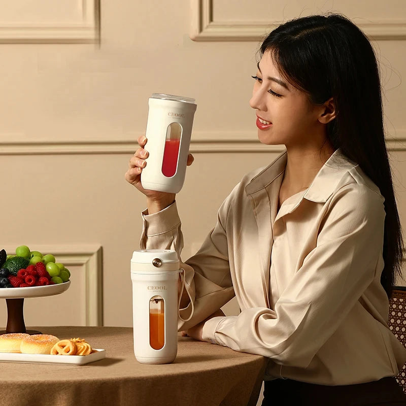 A woman sits at a table with two sleek, white portable blenders featuring clear windows for viewing drink contents.