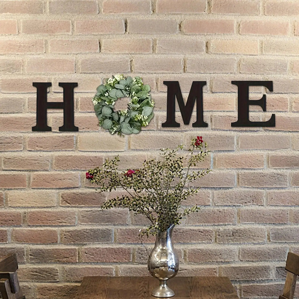 Rustic dark wooden 'HOME' wall letters with an artificial green eucalyptus wreath replacing the letter 'O'.