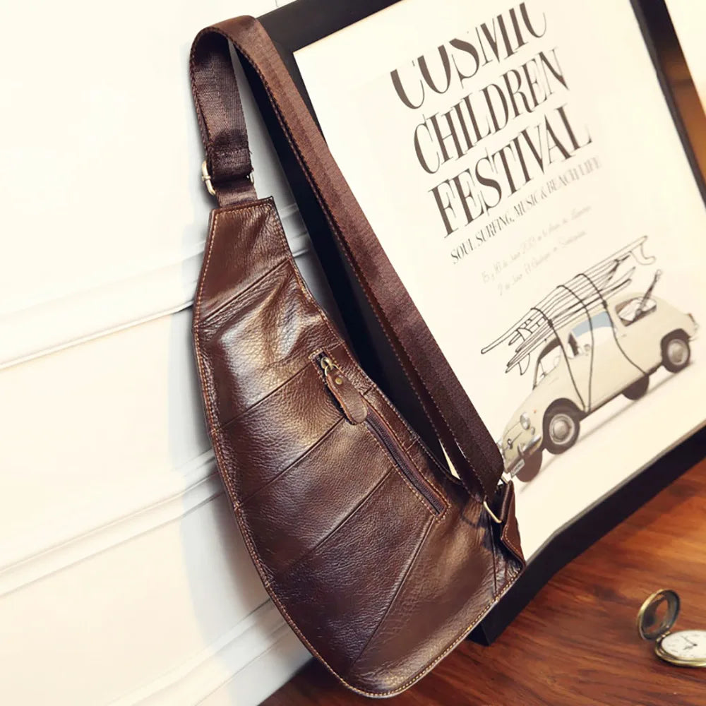 Dark brown leather crossbody sling bag with a textured finish, adjustable strap and a front zip pocket.