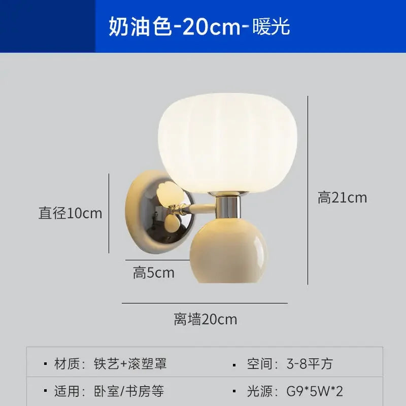 Cream-coloured wall lamp with a modern dual-globe design, featuring a ribbed glass shade and a warm glowing light.