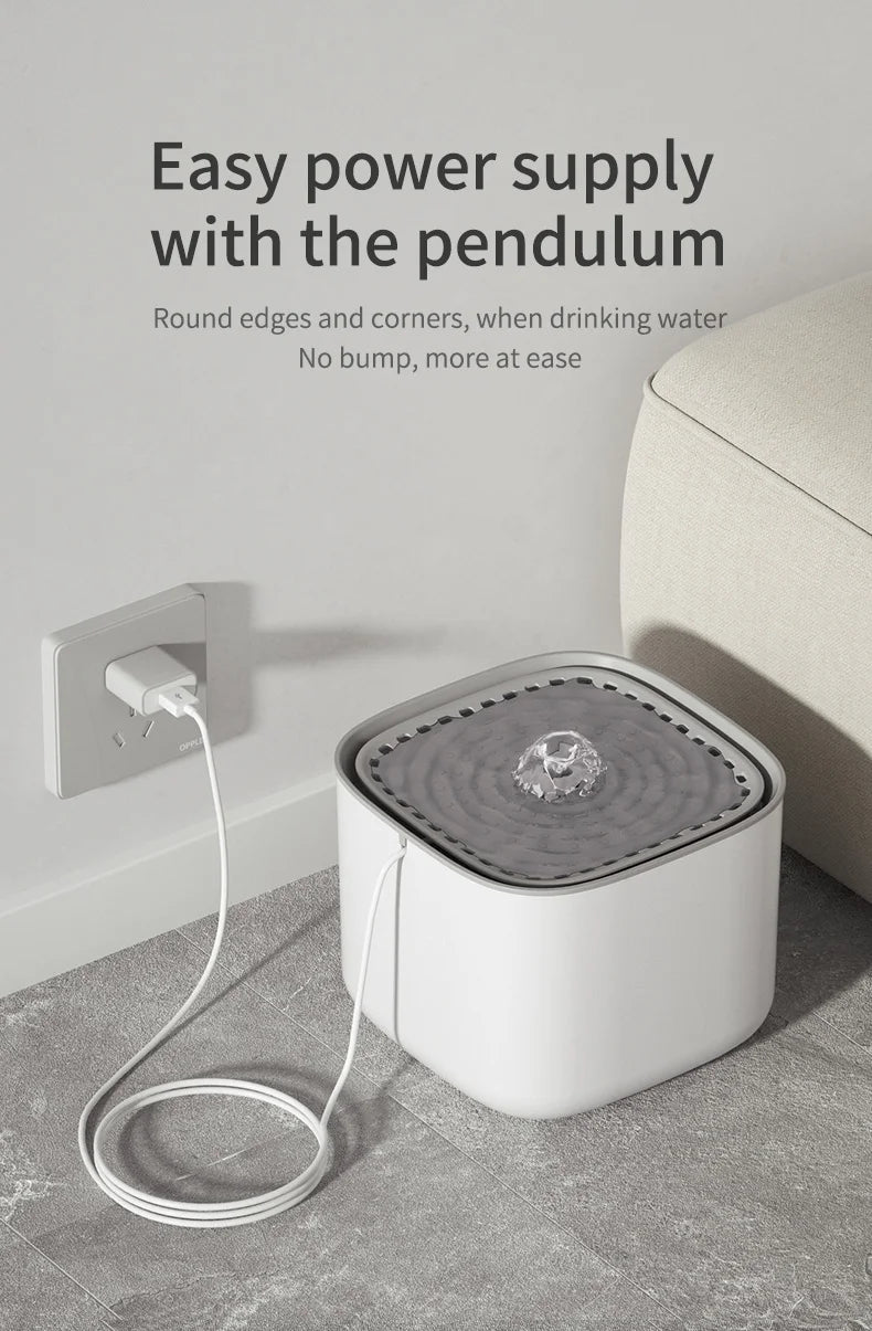 Minimalist white, square pet water fountain with a grey top basin and a USB power cable plugged into a wall outlet.
