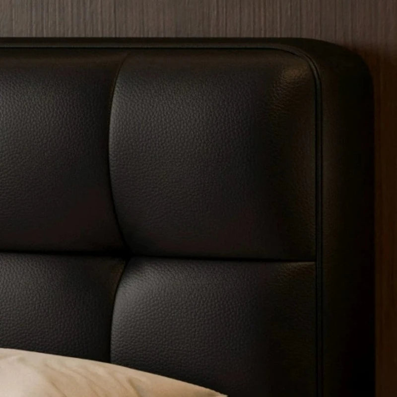 Close-up of a modern, black leather double bed headboard featuring soft, panelled cushioned detailing.