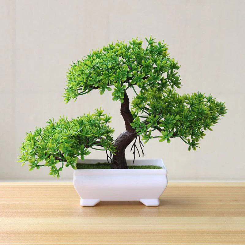 Artificial bonsai tree with vibrant green foliage and a brown trunk, sitting in a small, rectangular white pot.