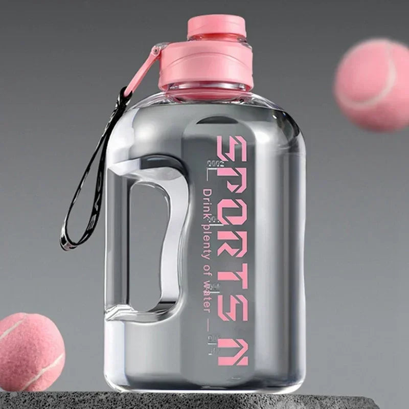 Clear sports water bottle with a pink lid, carry strap, and 'SPORTS' branding, set against grey with pink balls.