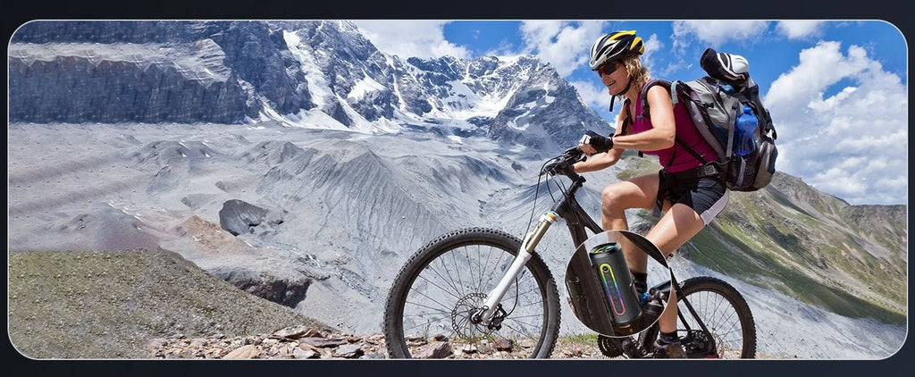 Cyclist on a mountain trail with a portable black Bluetooth speaker featuring colourful LED lights attached to the bike.