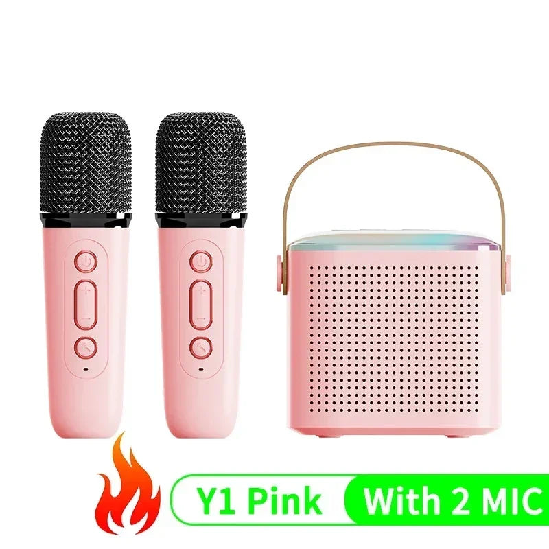 Pink portable karaoke speaker with a carry handle, two matching pink wireless microphones, and colourful RGB lighting.