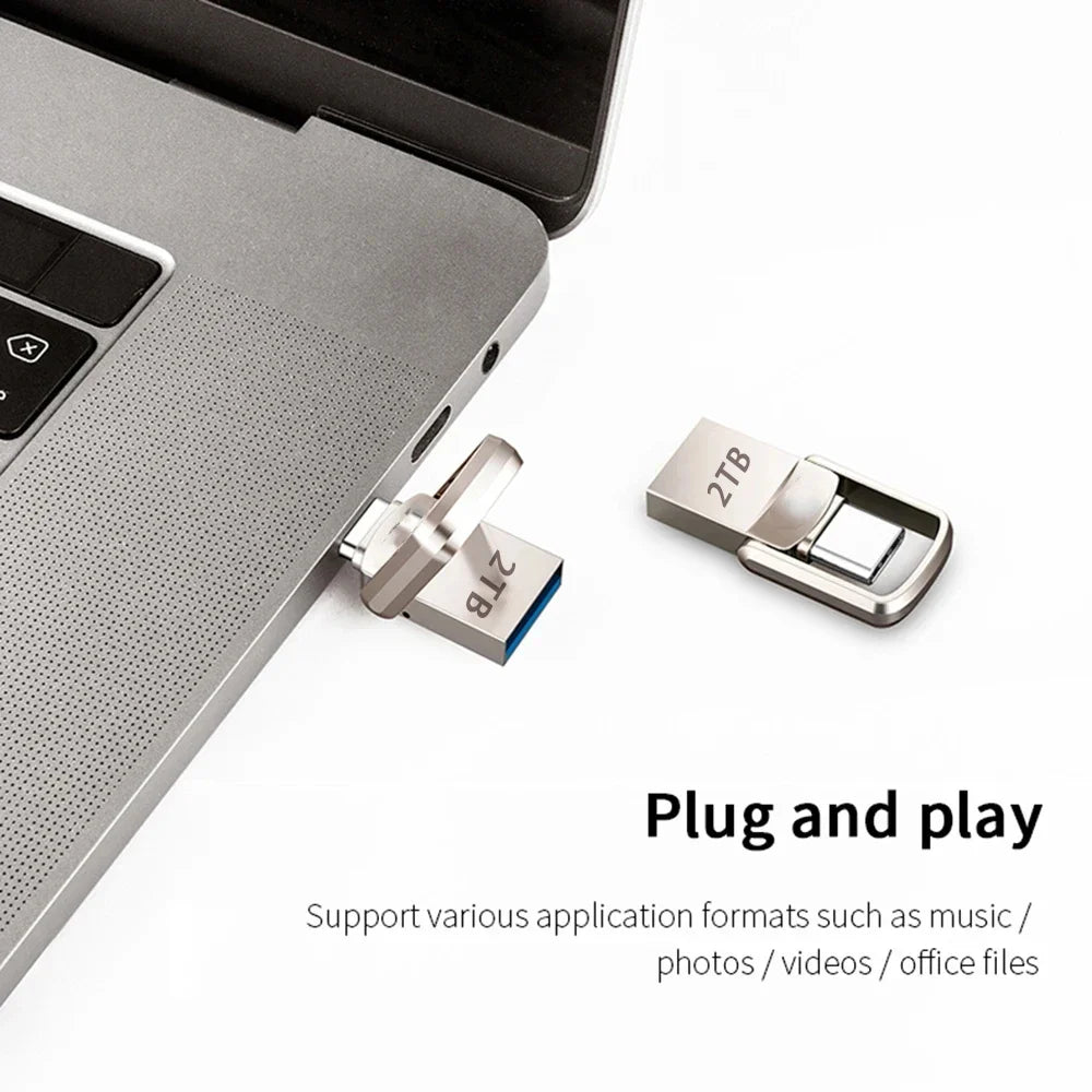 Sleek silver 2TB metal dual-connector flash drive plugged into a laptop, with a second unit shown beside it.