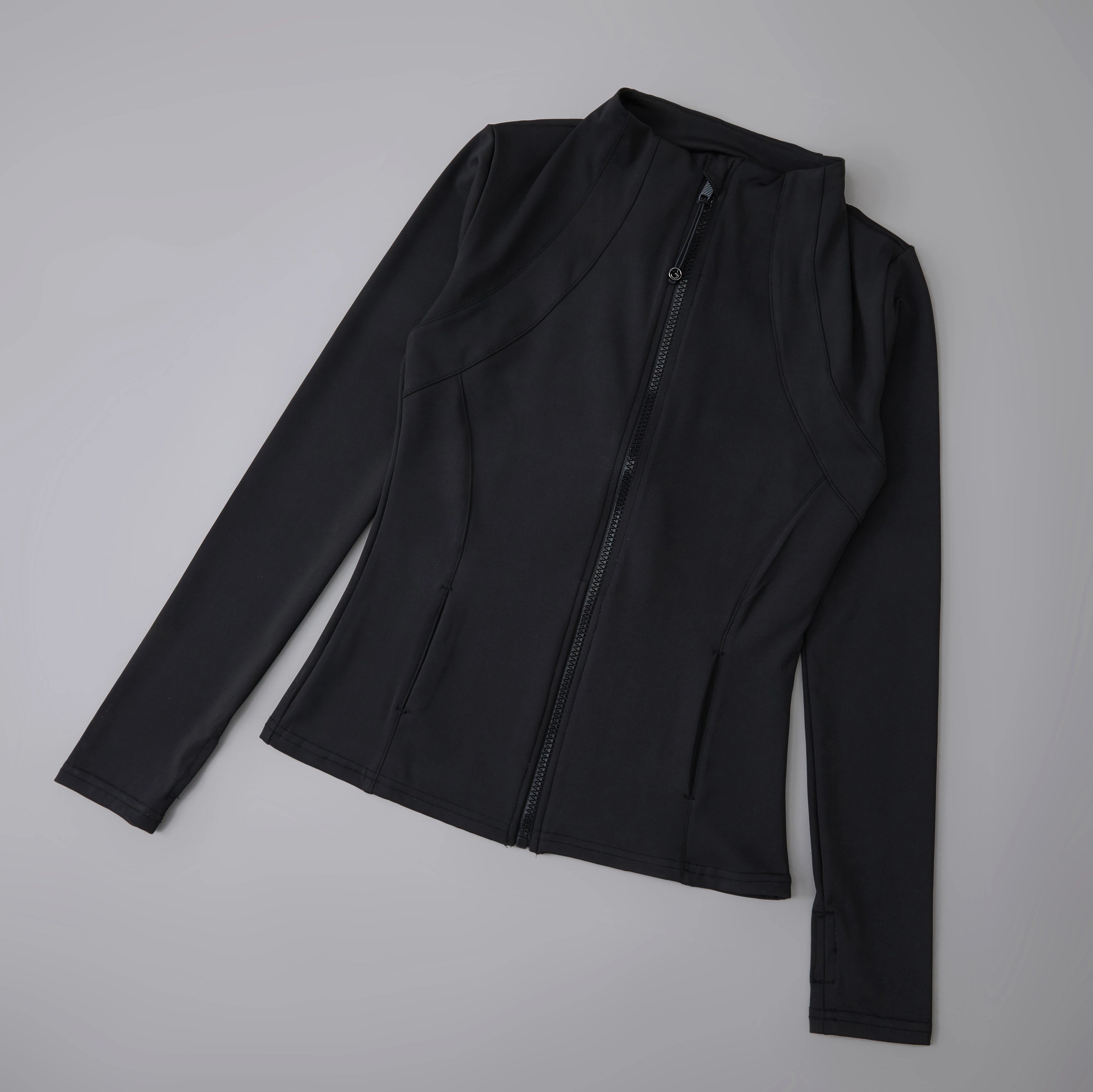 Black fitted women's athletic zip-up jacket with a high neck, long sleeves, and front pockets on a grey background.