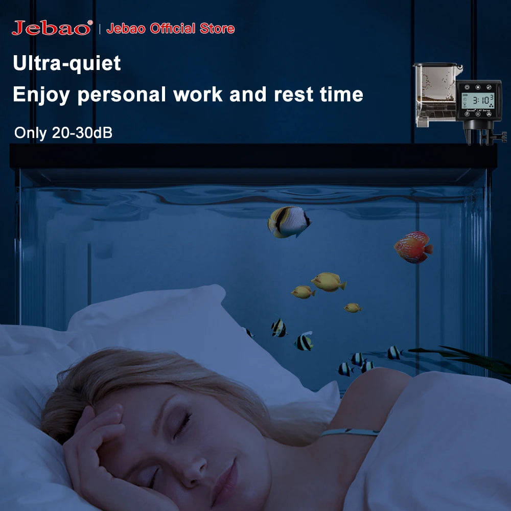 Black automatic aquarium fish feeder with a digital display mounted on a glass fish tank above a sleeping person.