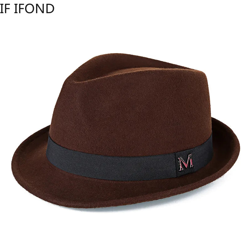 Classic brown wool felt fedora hat with a black grosgrain ribbon band and a decorative silver ‘M’ emblem.