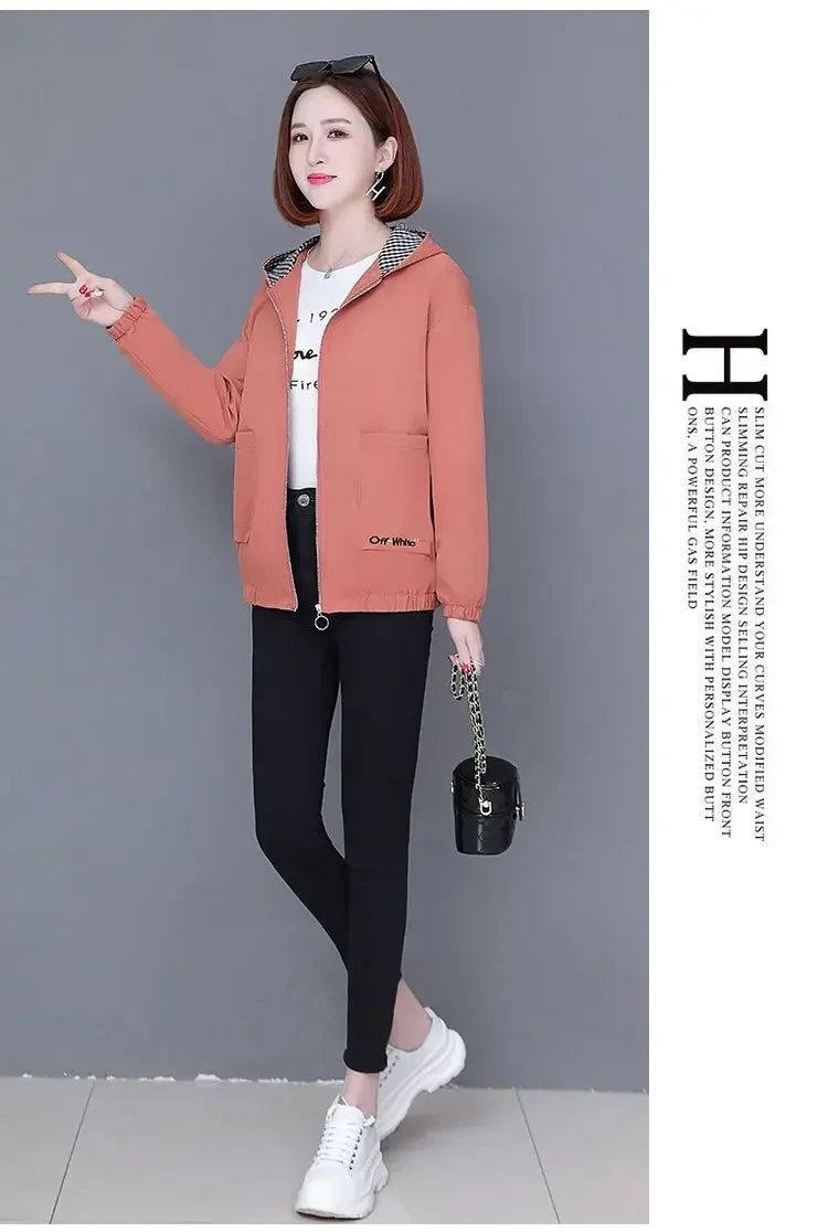 Woman wearing a dusty orange zip-up hooded jacket with a checkered inner lining, paired with black trousers.