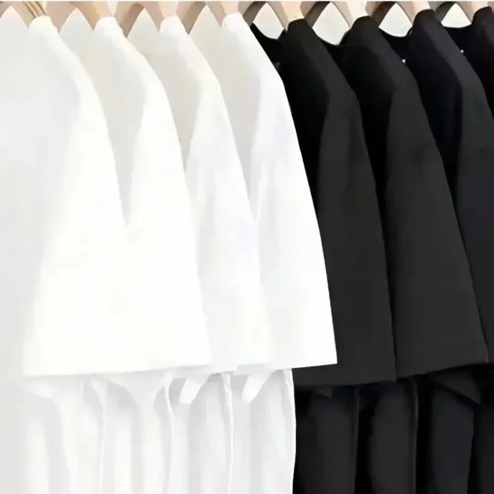 A row of plain short-sleeved t-shirts hanging on a rack, featuring both crisp white and classic black colour options.