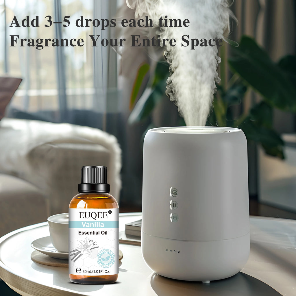 White minimalist oil diffuser emitting steam next to a bottle of vanilla essential oil on a living room table.