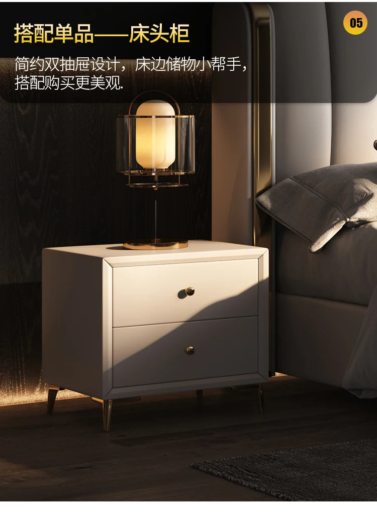 Minimalist off-white bedside table with two drawers, brass-tone handles, and slim gold legs. Modern aesthetic.