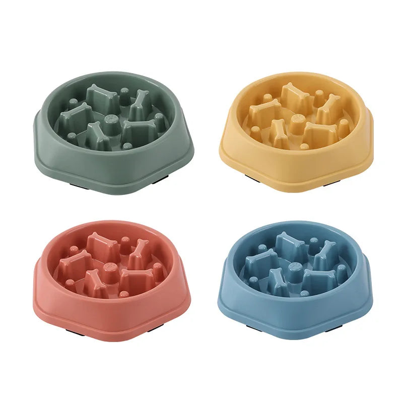 Four hexagonal slow-feeder pet bowls in sage, yellow, dusty rose, and blue, featuring internal bone-shaped obstacles.