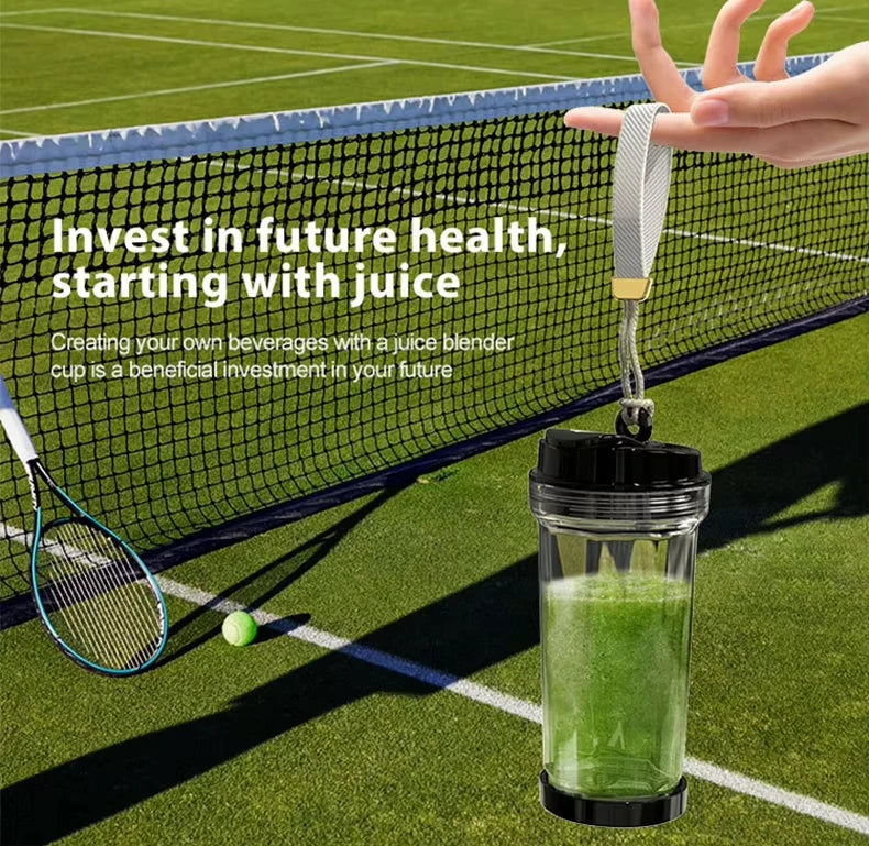 A portable, clear juice blender cup with a black lid and base, held by a grey fabric carrying strap.