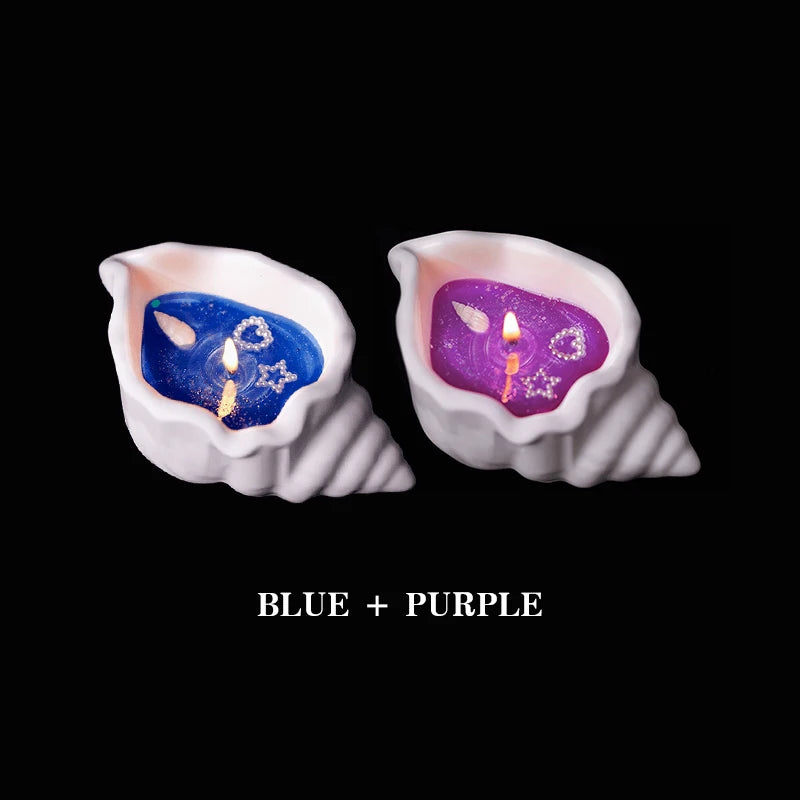 Two white shell-shaped candles with blue and purple wax, adorned with small pearl-look stars and hearts.