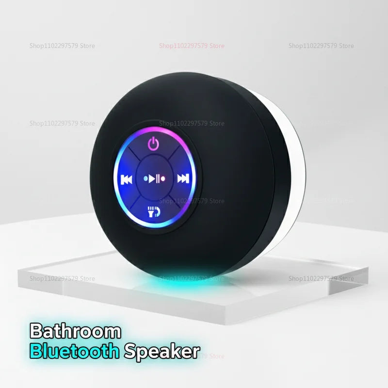 Compact black waterproof Bluetooth speaker with a central illuminated LED control ring, shown on a white surface.