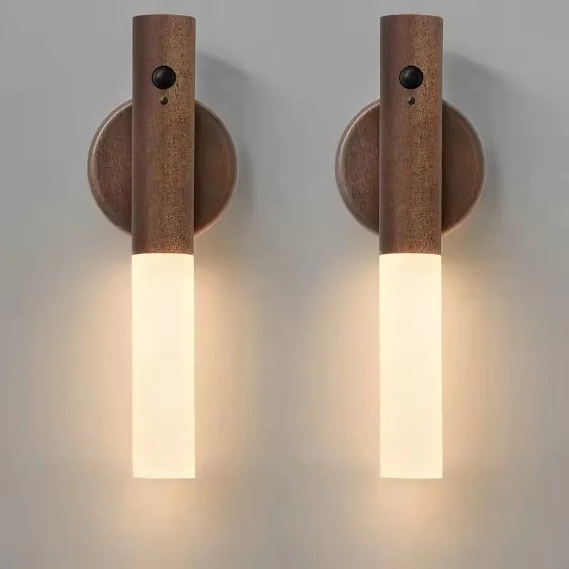 Two sleek, wall-mounted dark wood LED night lights with integrated motion sensors and soft, warm white illumination.