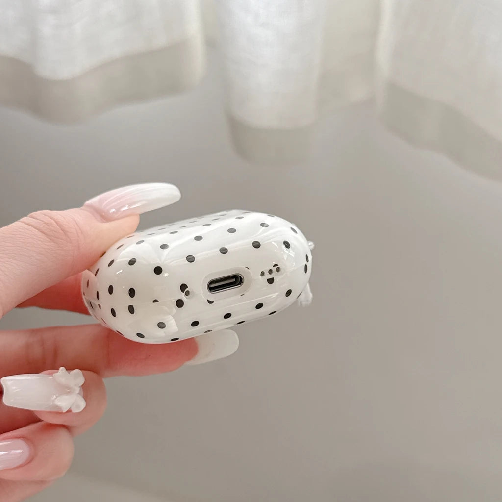 Clear, glossy AirPods Pro case with a black polka dot print, held by a hand.