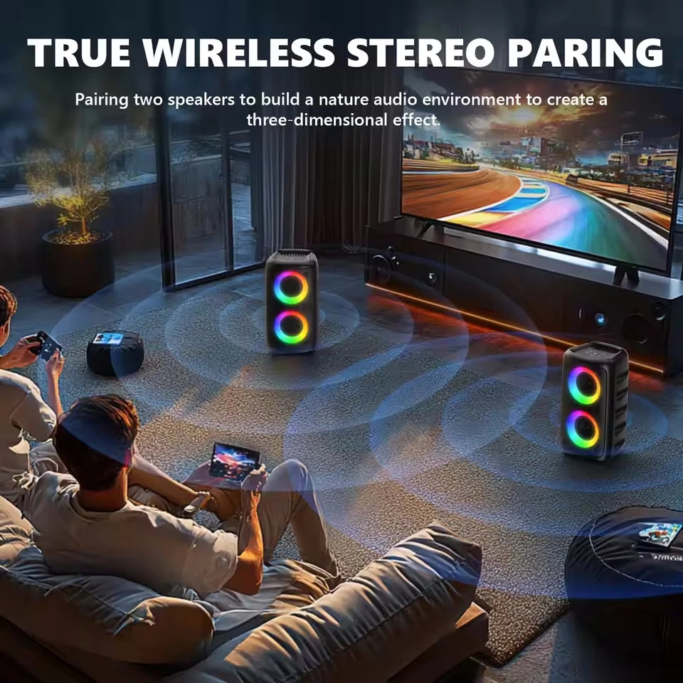 Two black portable karaoke speakers with colourful LED rings paired for wireless stereo sound in a living room.