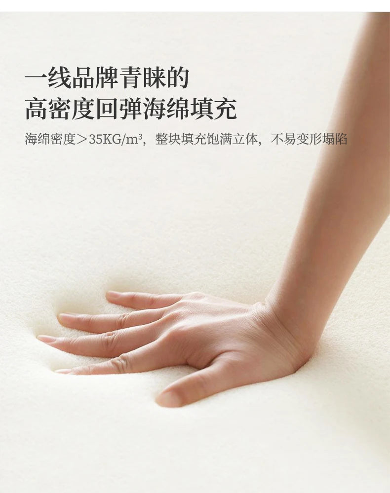 Close-up of a hand pressing into a high-density, cream-coloured foam mattress, showing its supportive texture.