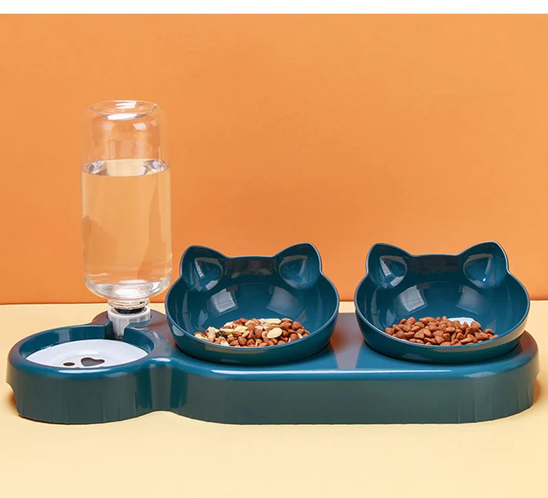 Teal pet feeding station with two cat-shaped bowls and an attached clear water bottle on an orange and yellow background.