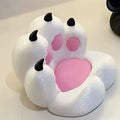 White cat paw-shaped chair with a soft pink seat, plush white textured upholstery, and black claw accents.
