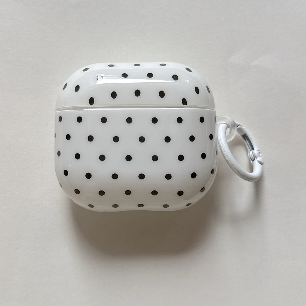 Glossy white AirPods Pro case with black polka dot pattern and attached white carabiner hook.