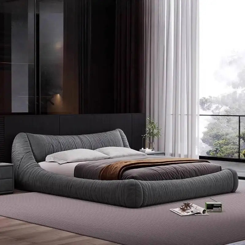 Modern low-profile charcoal grey upholstered bed frame with a textured, rounded design in a minimalist bedroom.