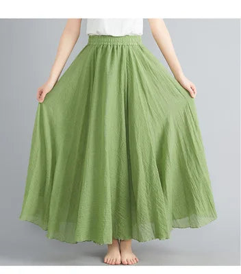 Sage green maxi skirt with a high elasticated waist and flared, textured fabric, worn with a white top.
