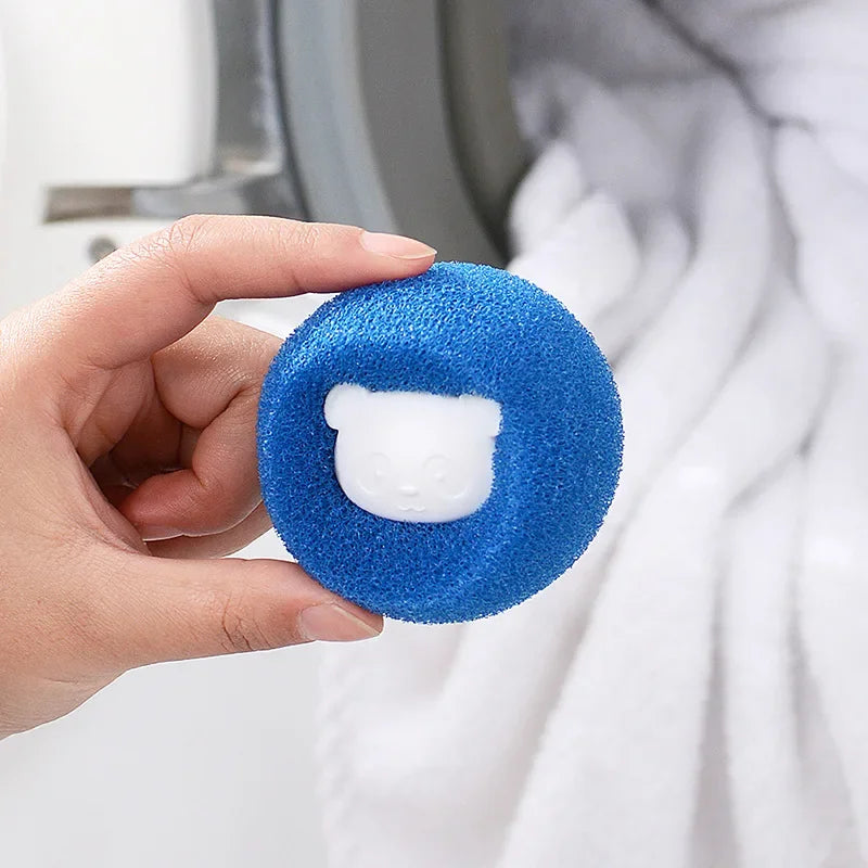 Hand holding a round, textured blue laundry cleaning sponge with a white bear face detail in the centre.