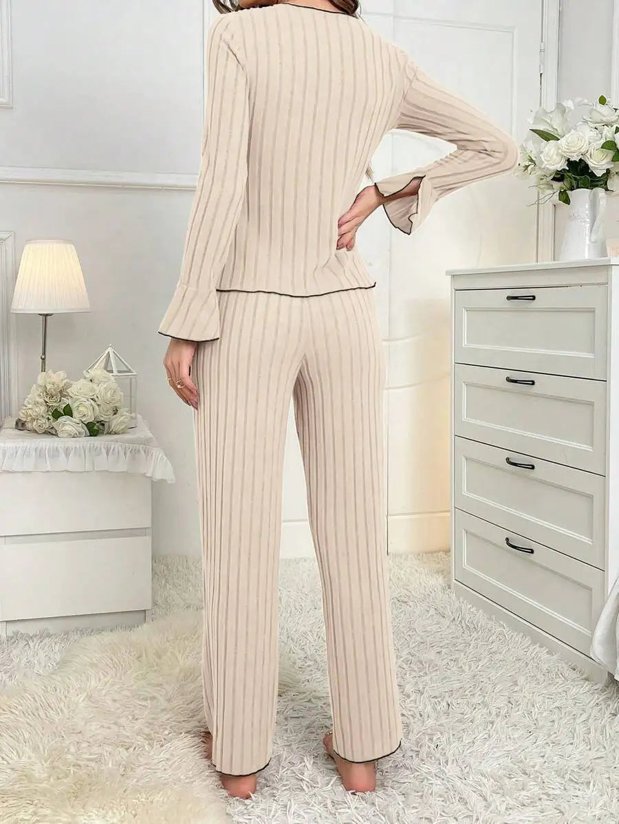 Beige ribbed loungewear set with long-sleeved top, flared sleeves, and wide-leg trousers, featuring black trim.