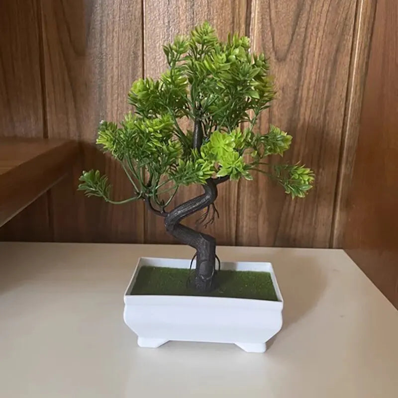 Small artificial bonsai tree with bright green plastic leaves and a curved brown trunk in a white rectangular pot.