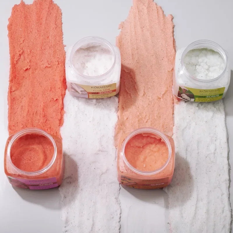 Four open jars of exfoliating body scrub with colourful textured product swatches on a white background.